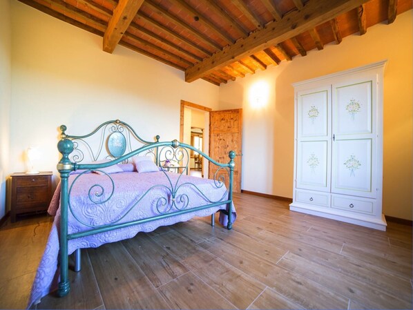 A bedroom with a bed, wooden floor, and a wardrobe.