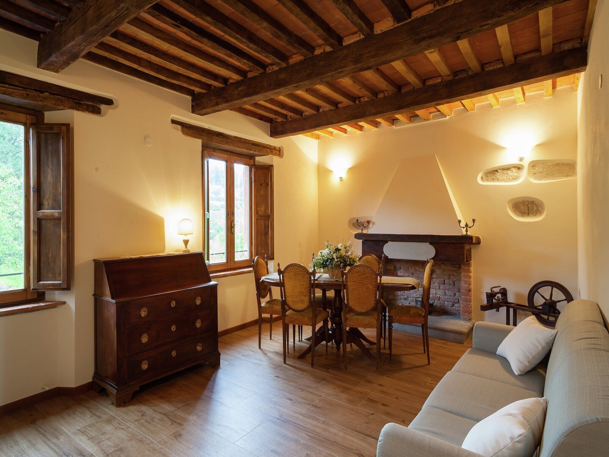 Un salon chaleureux avec un plafond en bois, une cheminée, une table à manger avec des chaises et un canapé.