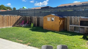 A backyard with a wooden playhouse, a slide, and a fenced area. - Homestay for rent.  House in a very quiet subdivision. (Les Essarts)