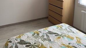 A bedroom with a bed, a wooden dresser, two wall-mounted shelves with decorative items, and a woven ceiling light fixture. - Homestay for rent.  House in a very quiet subdivision. (Les Essarts)