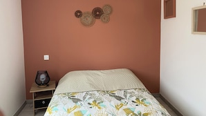 A bedroom with a bed, a bedside table, a lamp, and a wall-mounted decorative item. - Homestay for rent.  House in a very quiet subdivision. (Les Essarts)