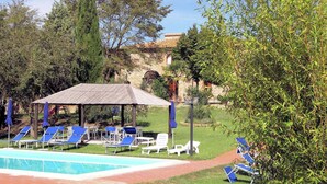 A pool area with lounge chairs and a gazebo. - Agriturismo in Tuscany with Pool and Wine Tasting (Peccioli)