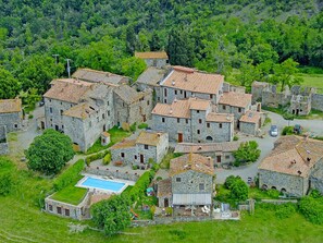 A stone village with traditional architecture, a central courtyard, and a swimming pool.