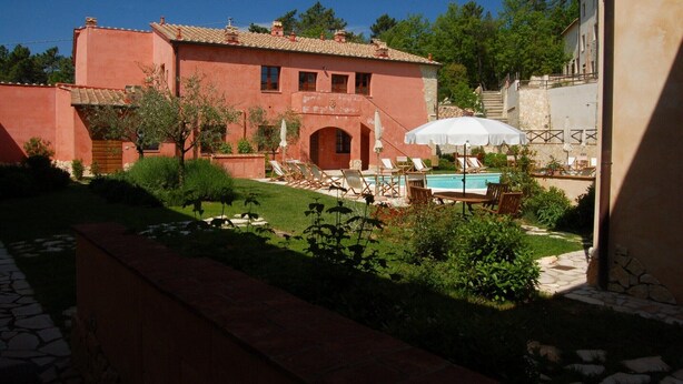 A red villa with a swimming pool, outdoor seating, and a stone pathway.