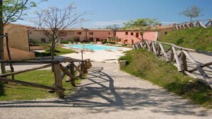A pool area with a wooden fence, a clear sky, and a building with a tiled roof.