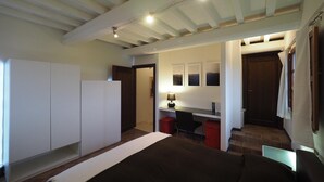 A bedroom with a bed, a desk, and a wardrobe.