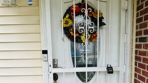 A white door with a decorative wreath, a doormat with the text "so happy," and a mailbox on the wall. - Colorful spacious 3 bedroom house near center  (Philadelphia)