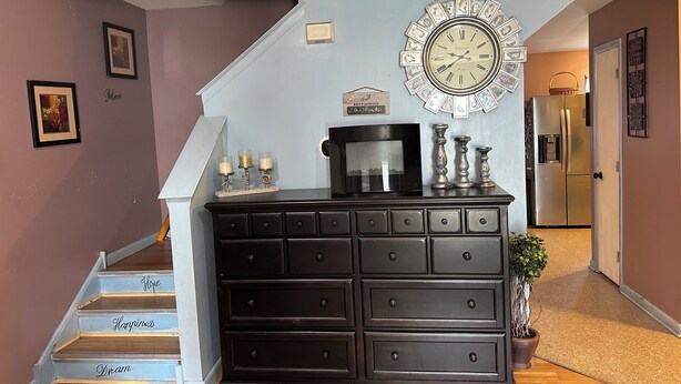 A staircase with steps labeled 'Hope,' 'Happiness,' and 'Dream.' A dark wooden dresser with multiple drawers is positioned against a wall, above which is a decorative clock. - Colorful spacious 3 bedroom house near center  (Philadelphia)