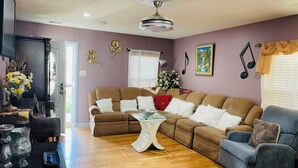 A living room with a sectional sofa, a glass coffee table, and a grey armchair. - Colorful spacious 3 bedroom house near center  (Philadelphia)