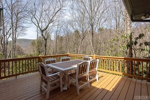 Enjoy a serene forest view from this deck with a table and chairs.