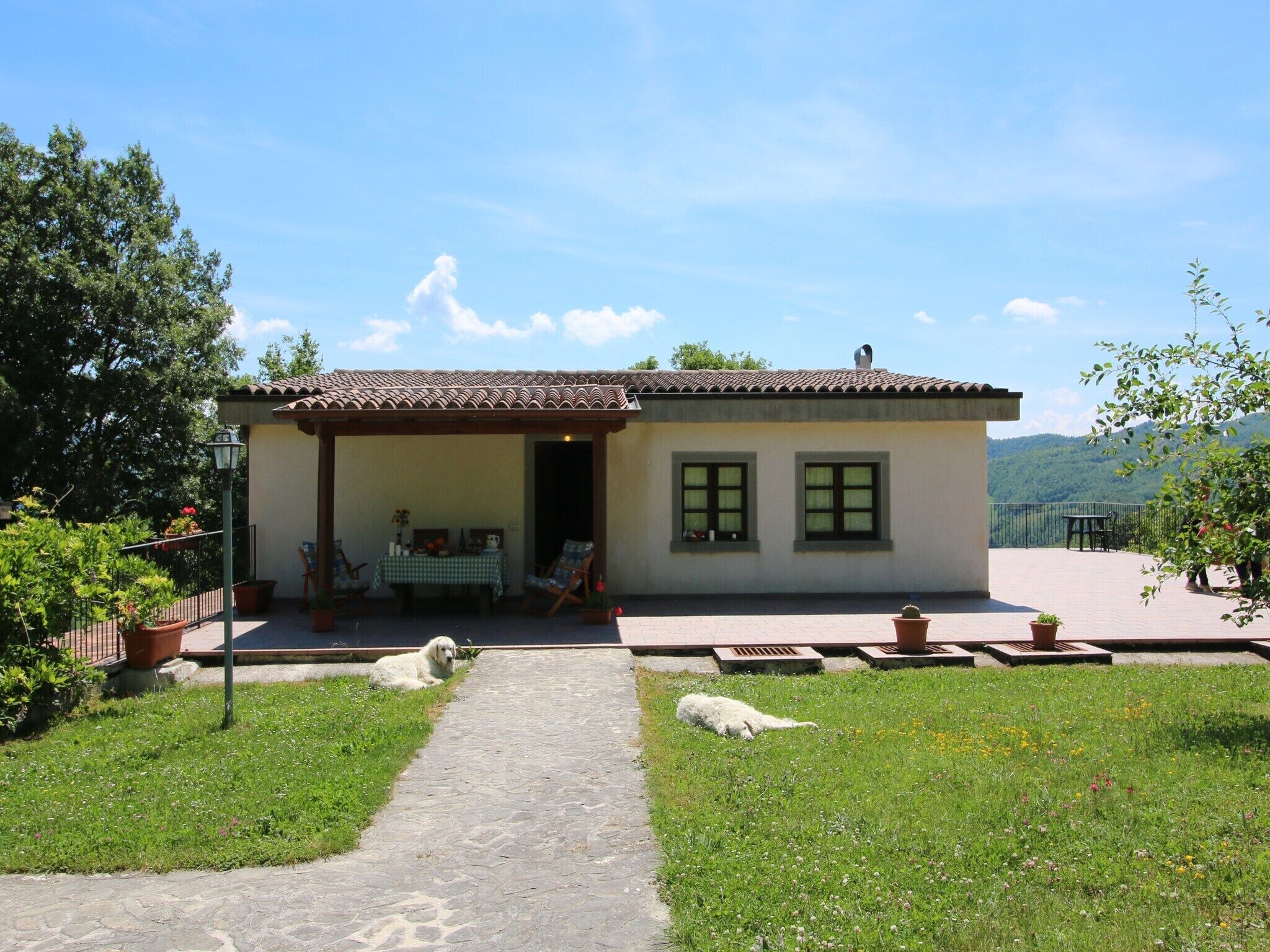 Ein kleines Haus mit einem Ziegeldach, einer überdachten Veranda und einem befestigten Weg zum Eingang.