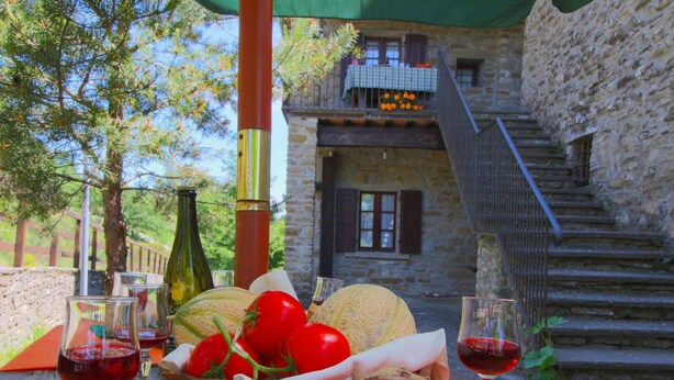 A table with food and drinks, a stone building, and a staircase in the background. - Farmhouse in Apecchio with Pool & Spa (Apecchio)