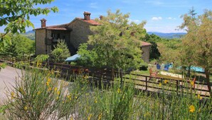 A rustic stone building with a tiled roof, surrounded by lush greenery and a clear blue sky. - Farmhouse in Apecchio with Pool & Spa (Apecchio)