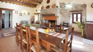 A dining area with a stone fireplace, wooden ceiling beams, and a rustic aesthetic. - Farmhouse in Apecchio with Pool & Spa (Apecchio)