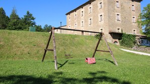 A grassy area with a swing set and a building in the background. - Mansion in Apecchio with Pool (Apecchio)