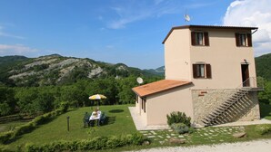 A two-story building with a stone staircase and a small balcony. - Mansion in Apecchio with Pool (Apecchio)