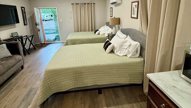 A hotel room with two beds, a sofa, a TV, and a desk.