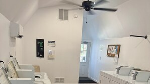 A laundry facility with multiple washing machines, a ceiling fan, and a drop box.