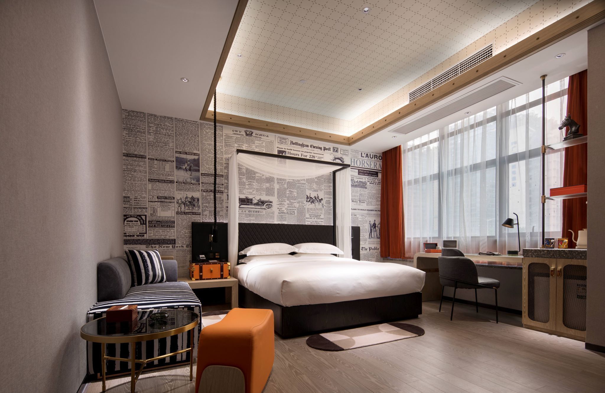 Ein modernes Hotelzimmer mit einem großen Bett, einem Schreibtisch, einem Stuhl und einer kleinen Sitzecke.