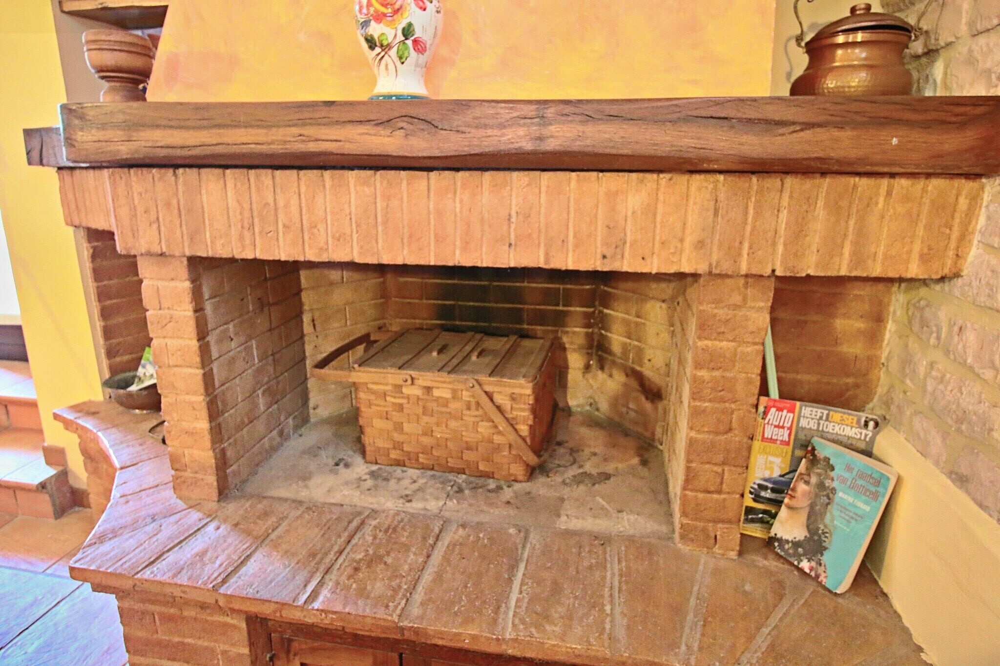 Une cheminée en briques surmontée d’une cheminée en bois, un panier en osier et un magazine sont placés sur le côté droit.