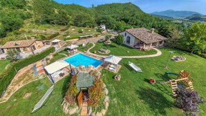 A villa with a swimming pool, a garden, and a view of the surrounding hills.