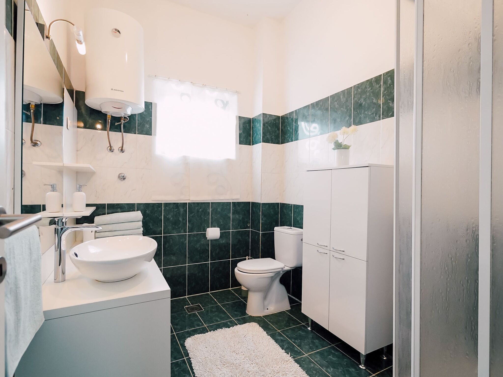 Un baño moderno con lavamanos, inodoro y tocador blancos.