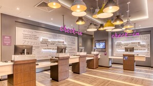 A hotel reception area with check-in counters, a large wall with inspirational quotes, and a modern design. - Premier Inn Dublin Cc North Docklands (Dublin)