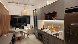 A modern kitchen with a dining area, featuring a built-in microwave, a refrigerator, and a sink.