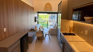 A modern kitchen with a dining area, a view of the outdoors, and a hanging light fixture.
