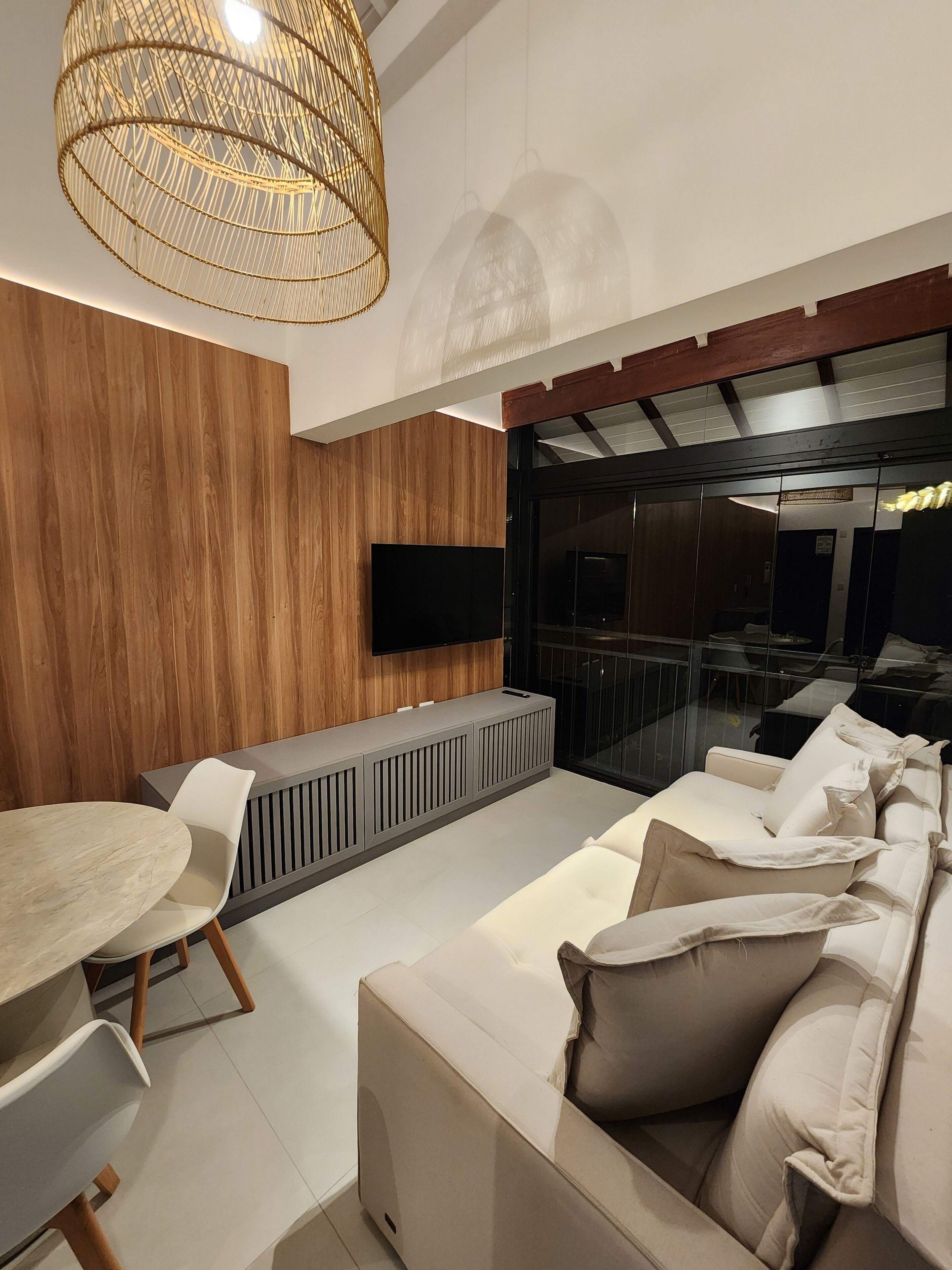 Una sala de estar moderna con una pared de madera, un televisor de pantalla plana, un sofá y un comedor con mesa y sillas.
