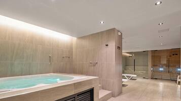 Un baño moderno con una bañera grande, zona de ducha y tocador con espejo.
