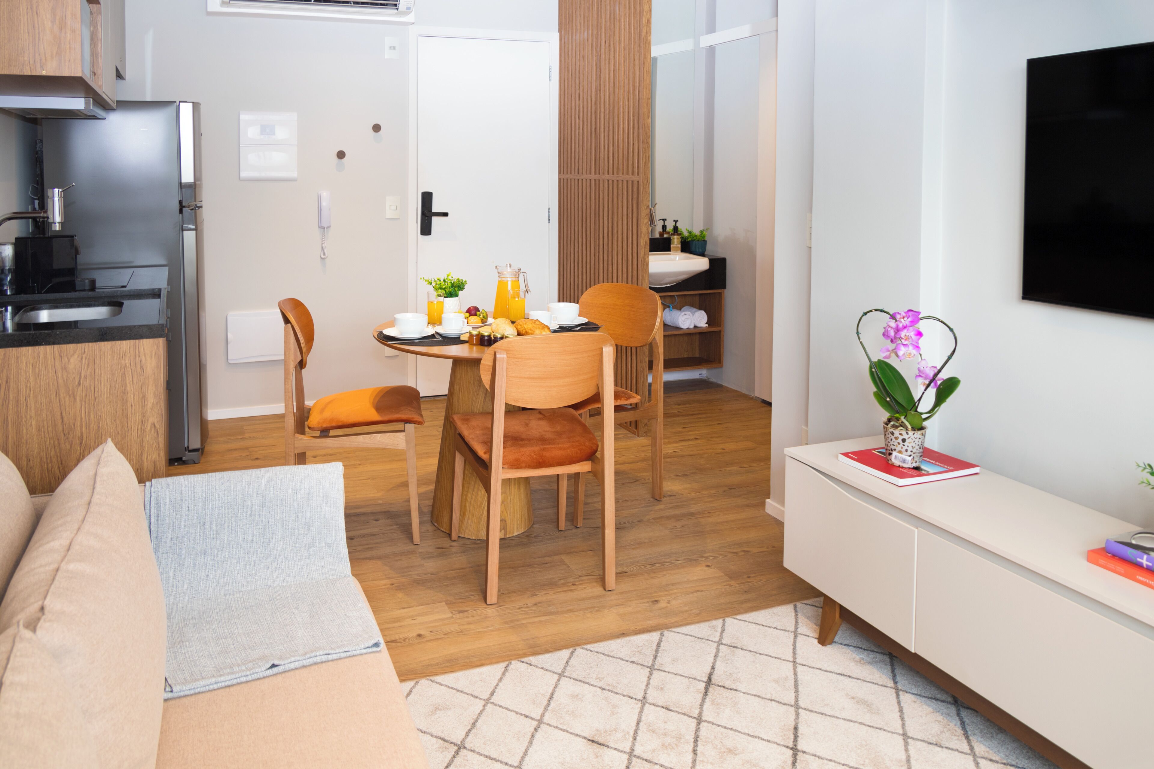 Une chambre d’hôtel moderne dotée d’une kitchenette, d’un coin repas et d’un espace de vie.