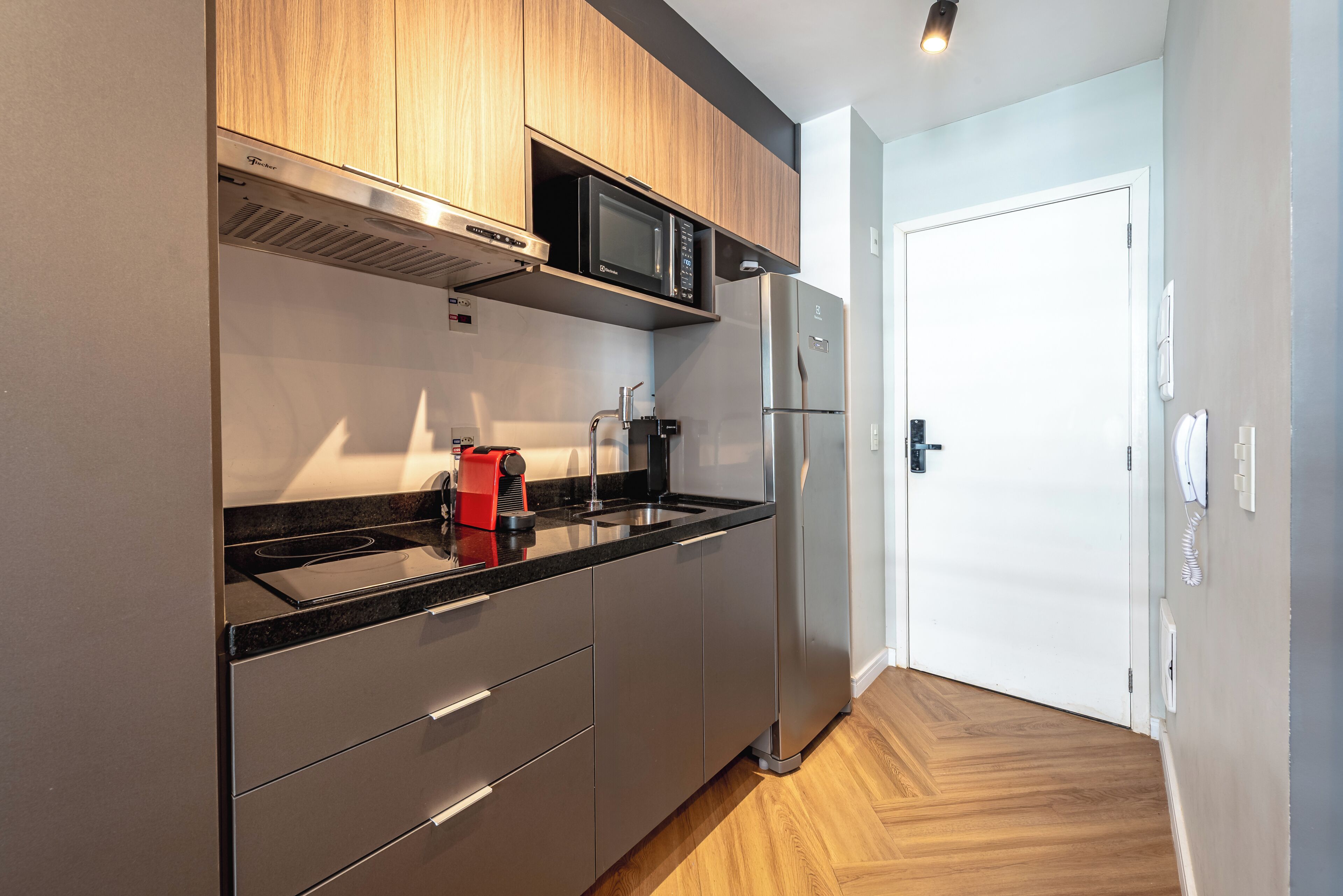 A modern kitchen with stainless steel appliances, wooden cabinets, and a black countertop.