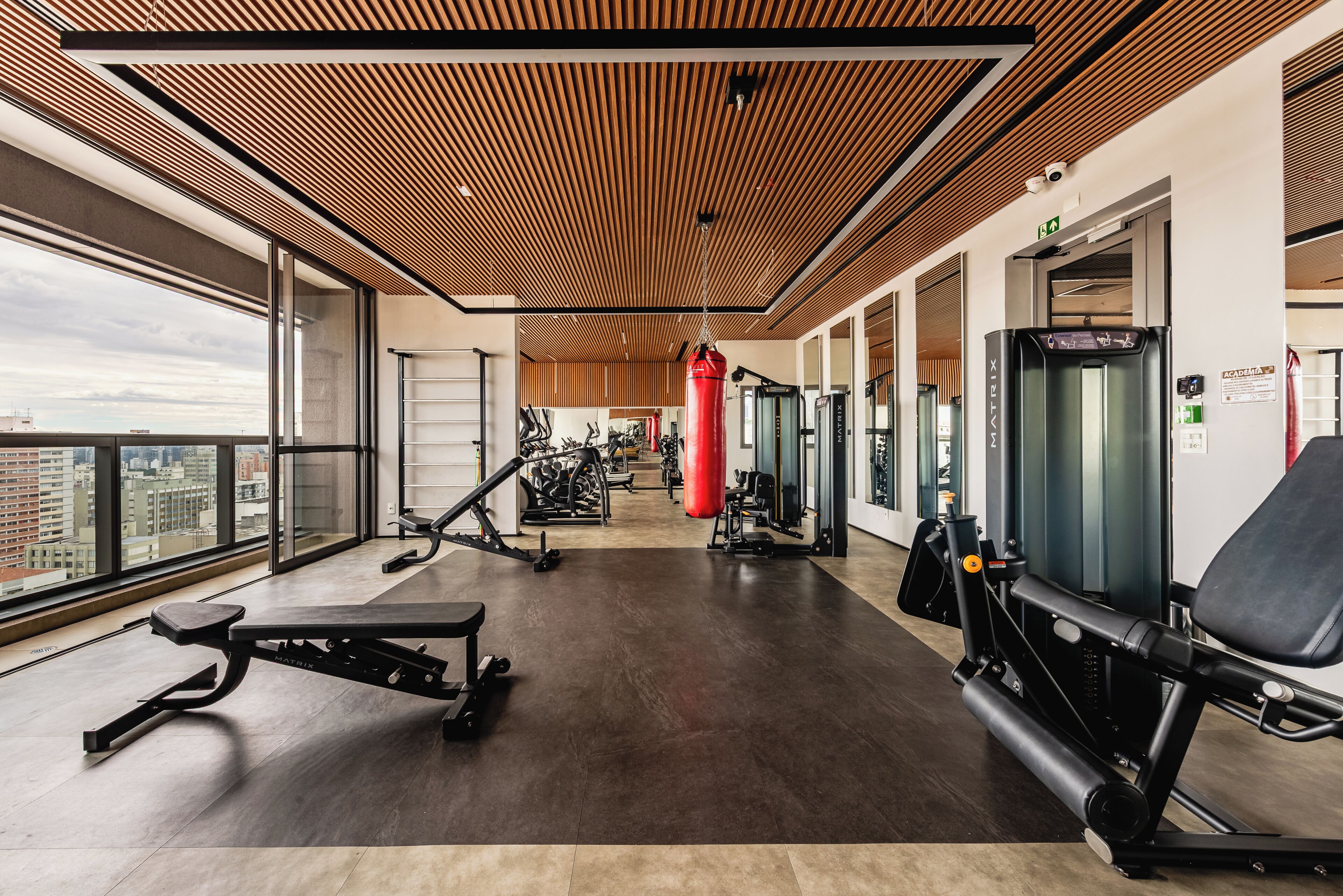 A gym with exercise equipment, large windows, and a city view.