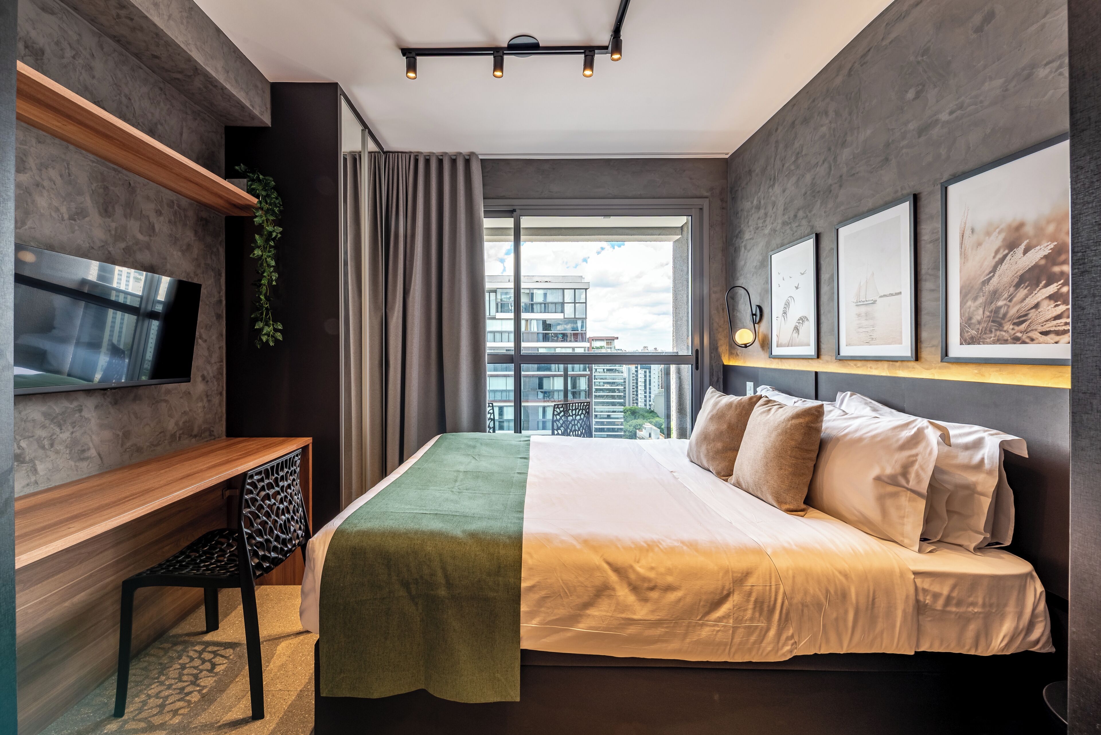 Ein modernes Hotelzimmer mit Bett, Schreibtisch, Fernseher und Balkonblick.