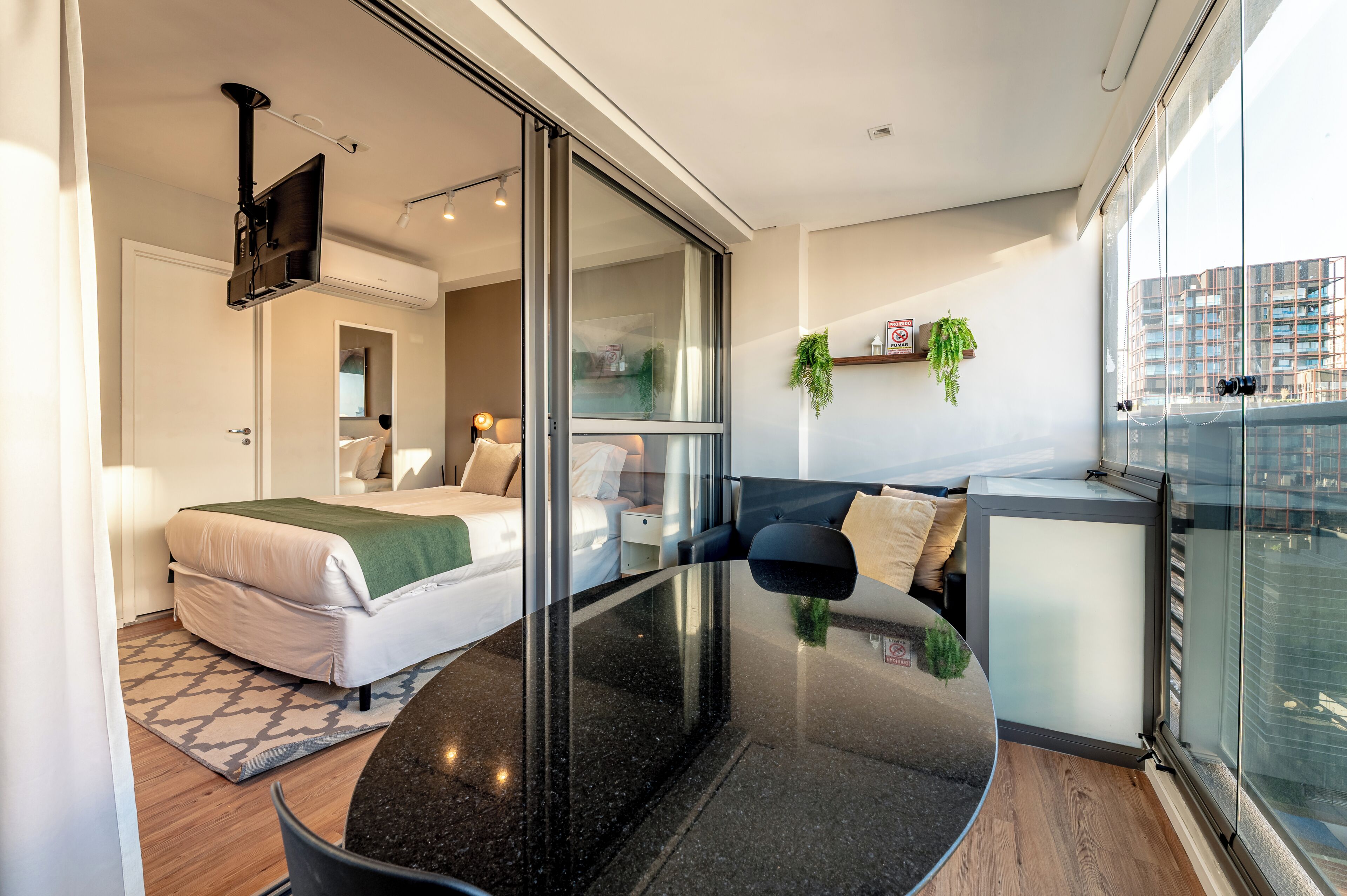 A modern bedroom with a bed, bedside table, and a TV mounted on the wall.