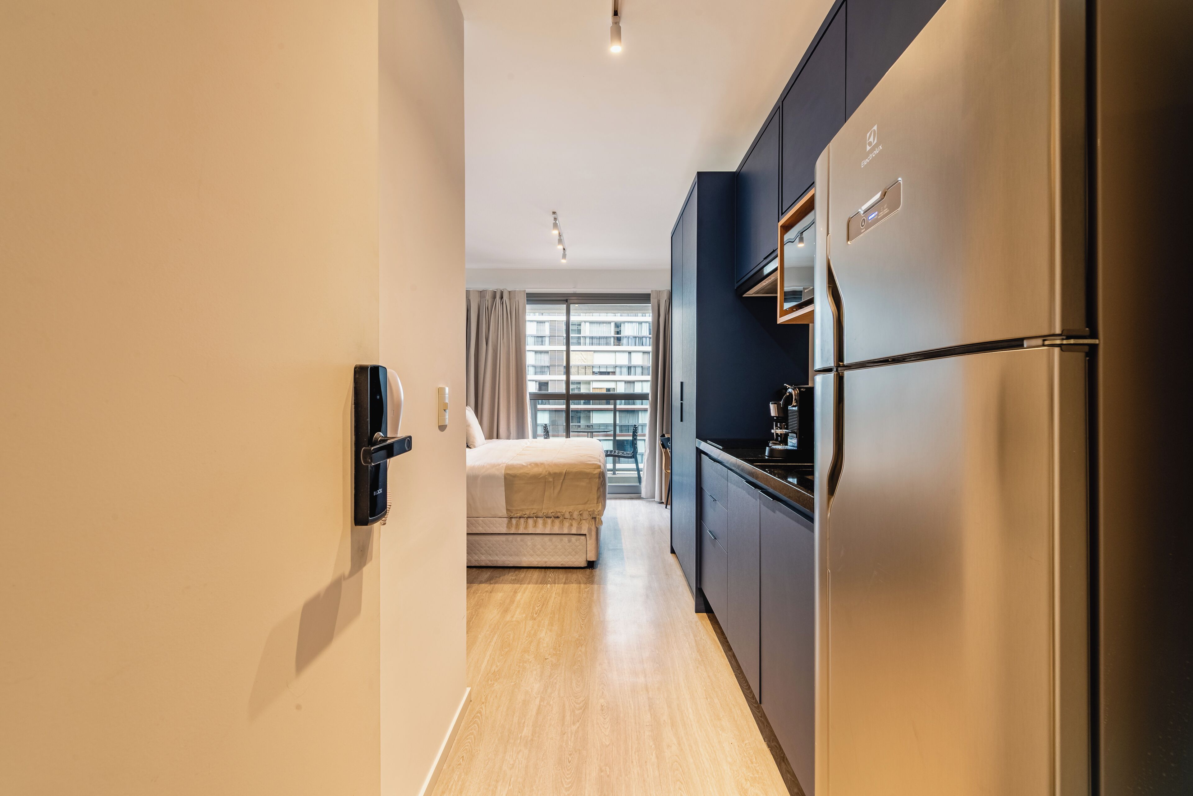 Una camera d'albergo moderna con angolo cottura, un letto e vista sulla città.