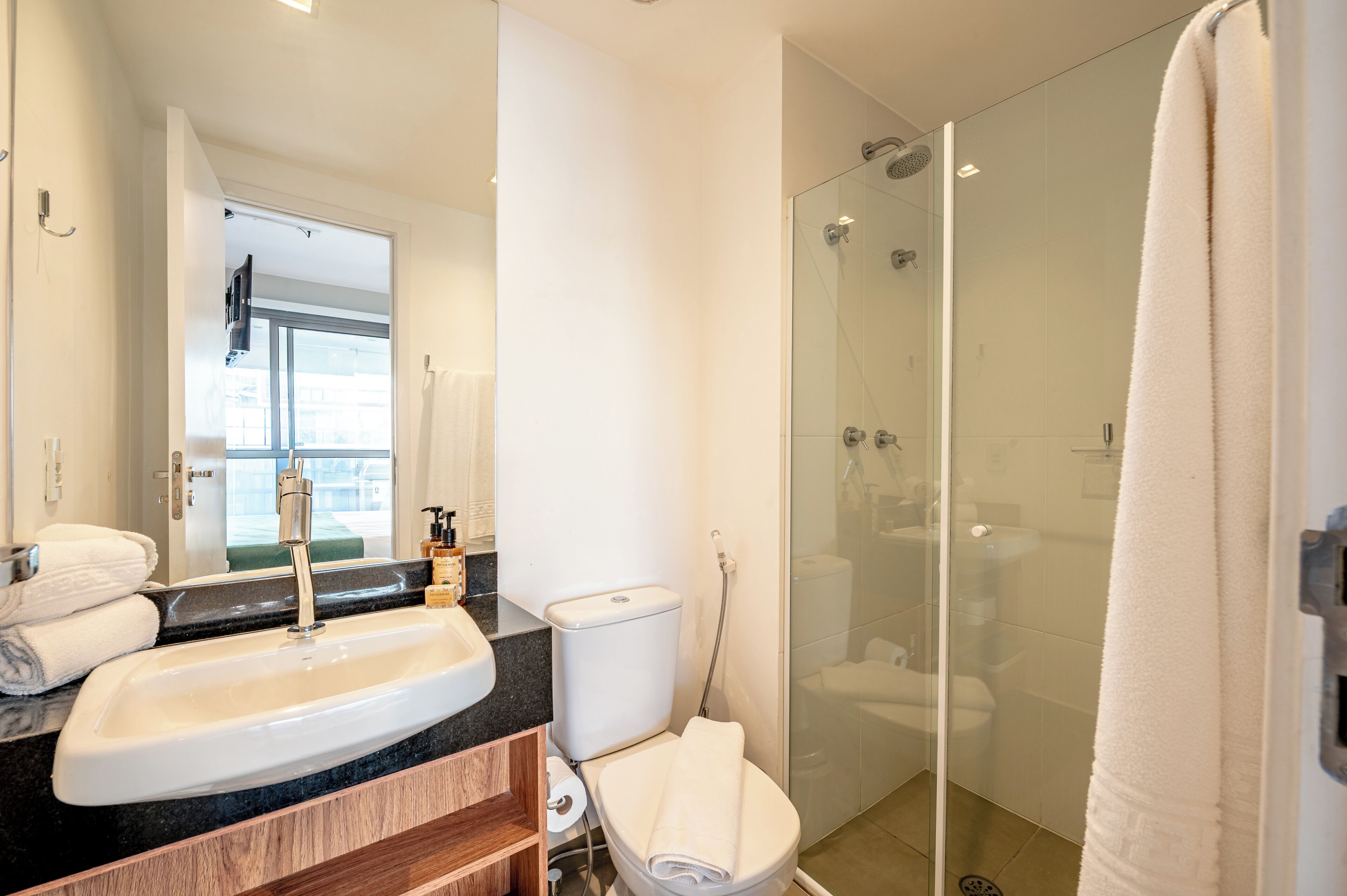 Un baño moderno con lavamanos, inodoro y ducha con mampara de vidrio.