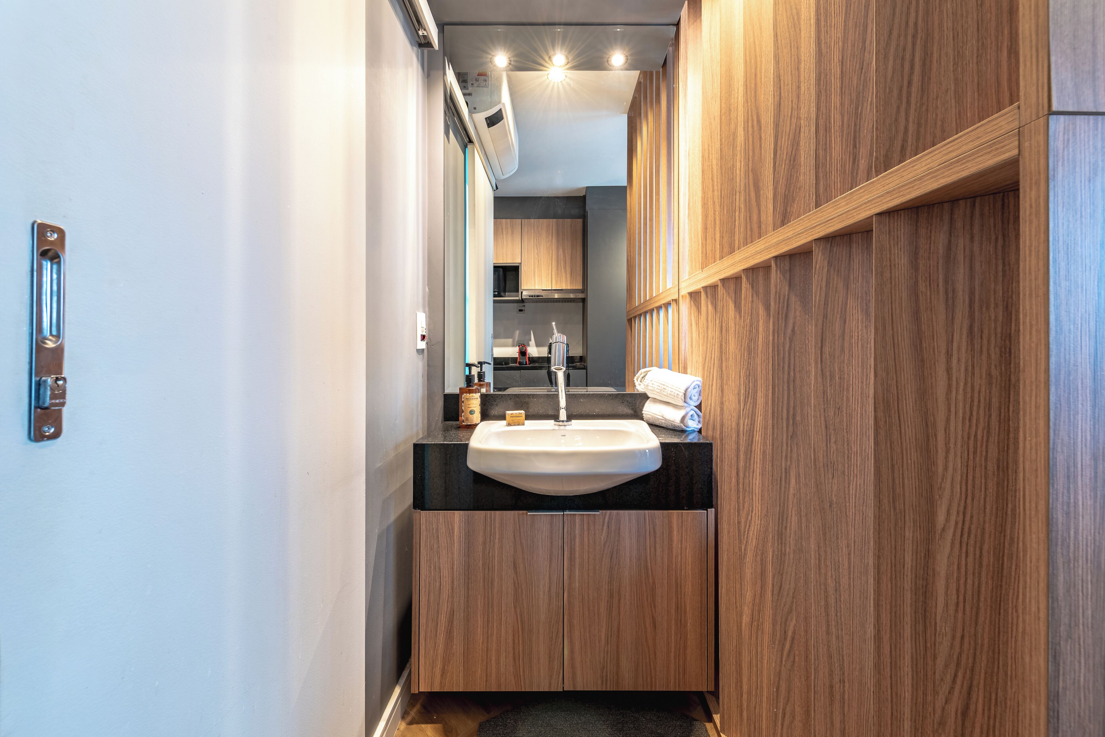 A modern bathroom with a sink, wooden cabinets, and a visible shower area.