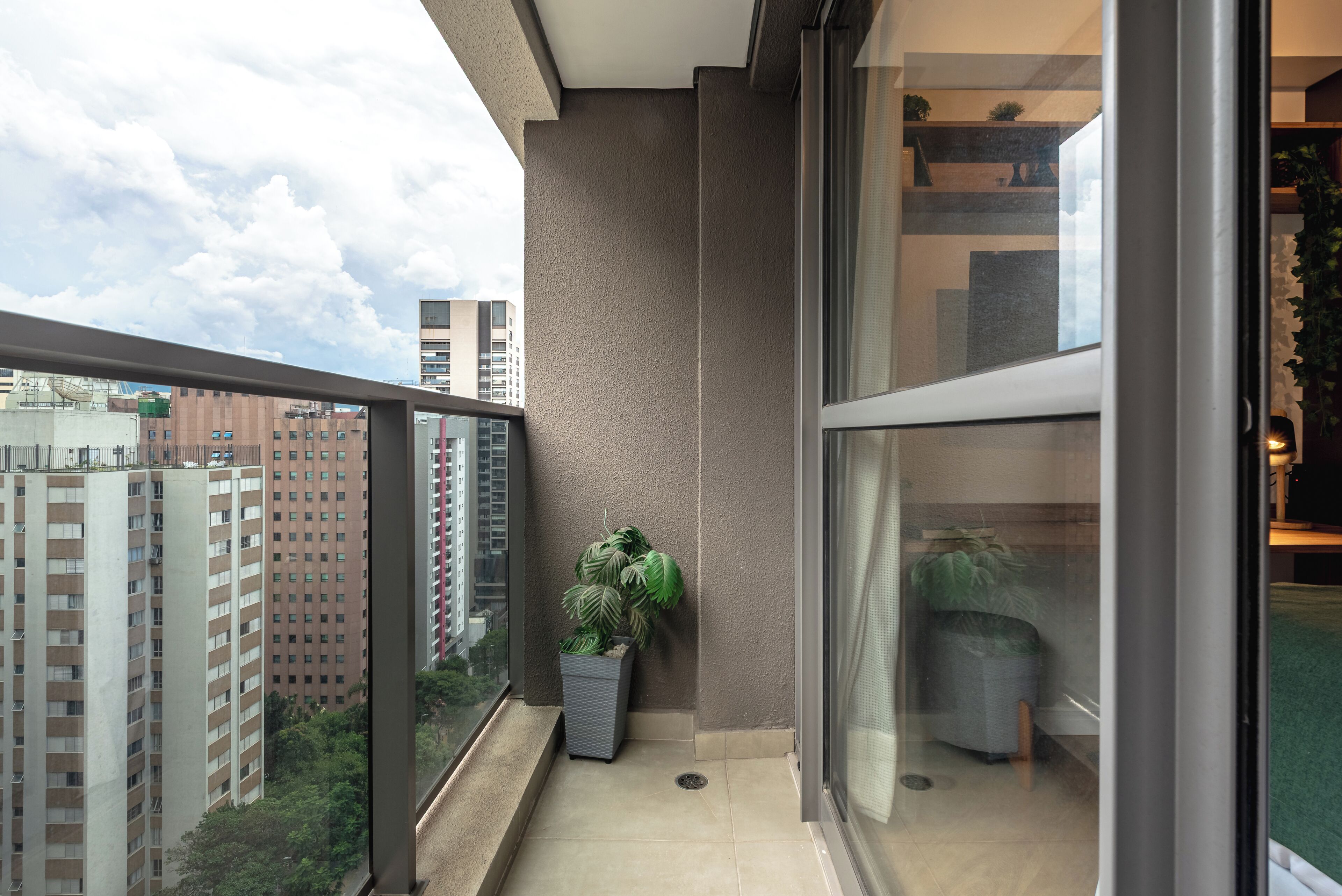 A balcony with a potted plant, a window, and a view of buildings.