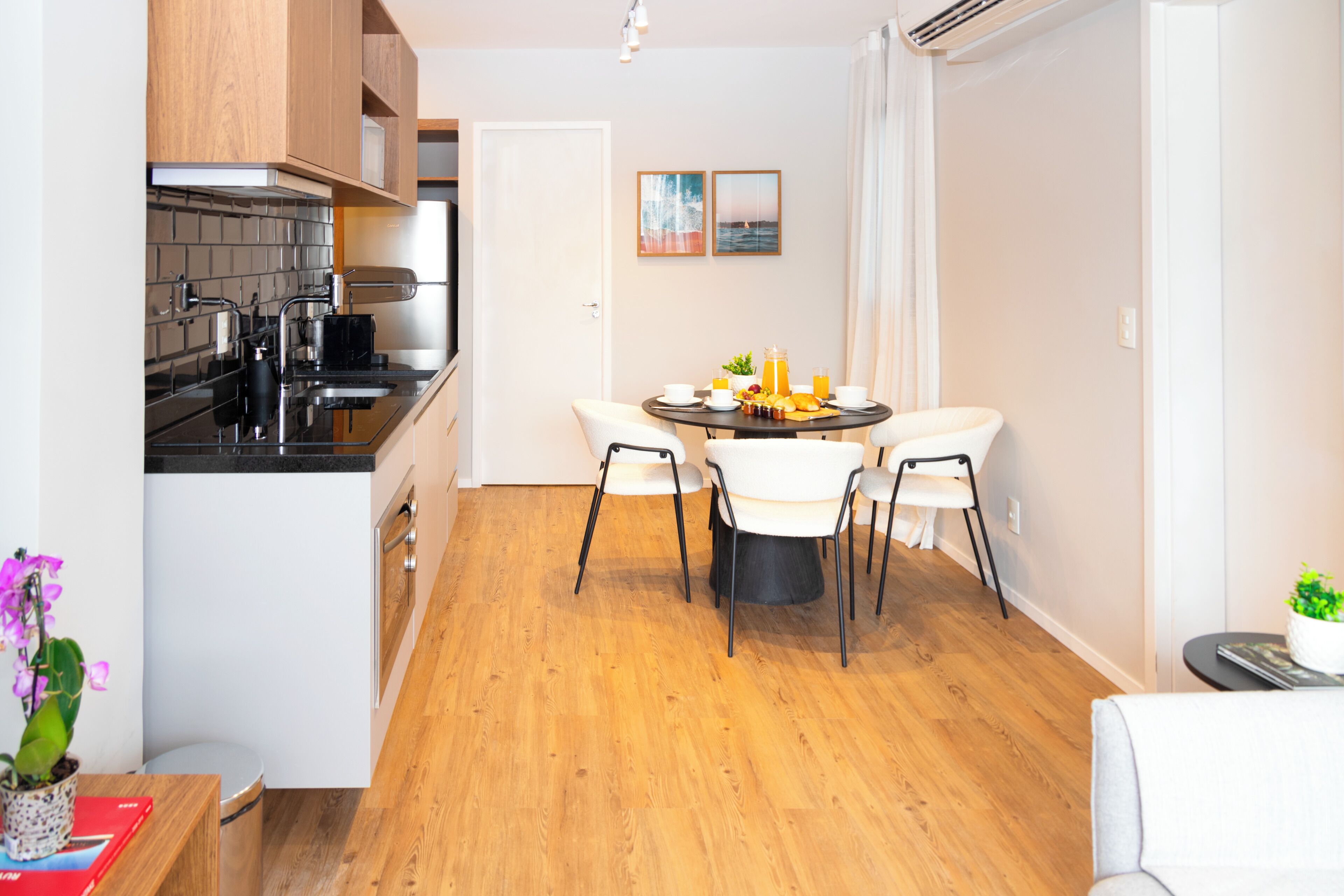 A modern kitchen with black countertops, white cabinets, and a dining area with a round table and four chairs.