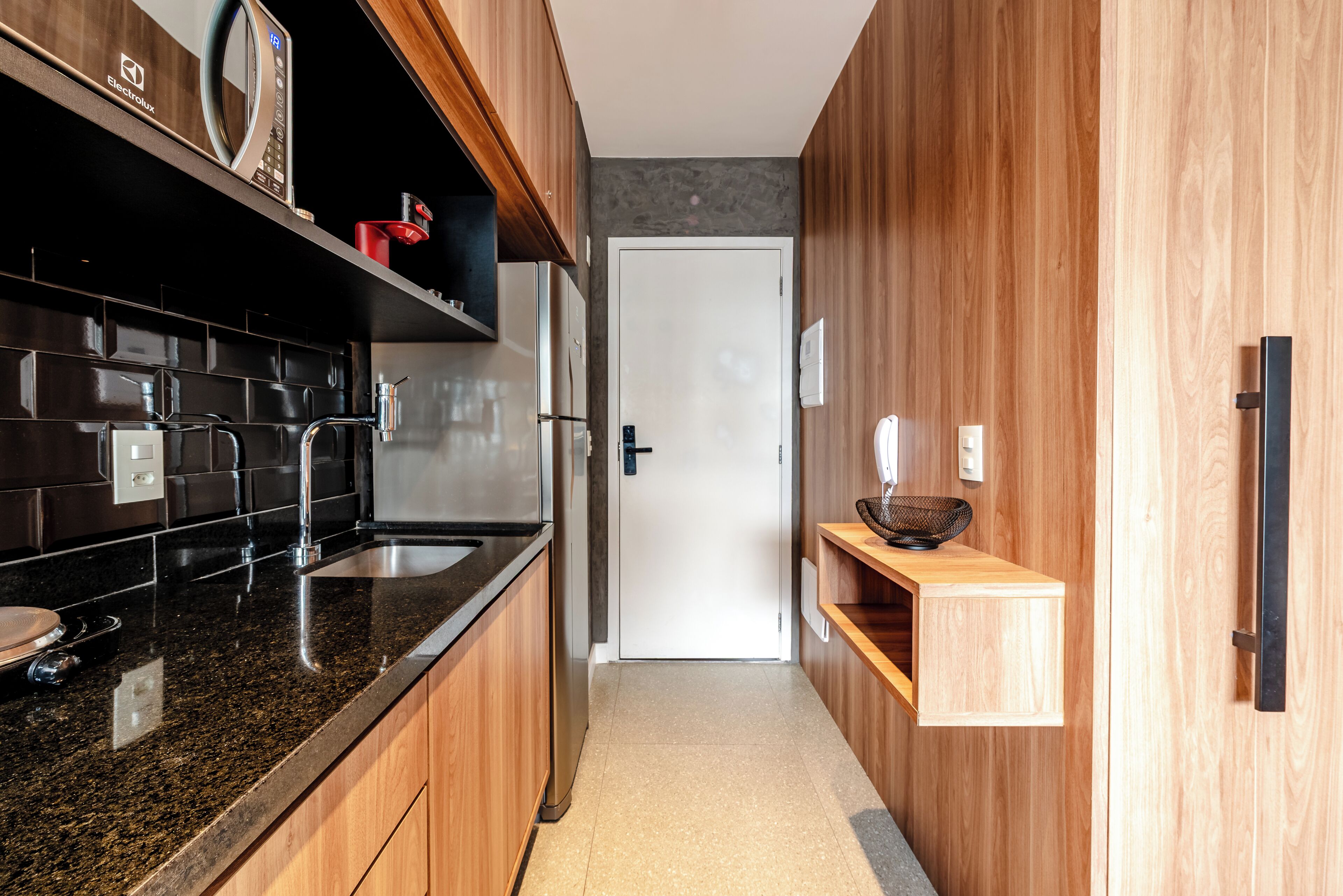 A modern kitchen with dark granite countertops, stainless steel appliances, and wooden cabinetry.