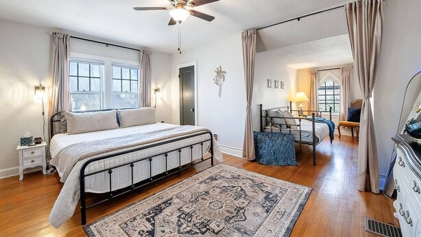 A bedroom with a bed, a ceiling fan, a window, a nightstand, a dresser, and a rug. - Clifton Corner: Art Deco charm in College Hill. Walk to the park, dining & shops. 2 king beds. (Wichita)