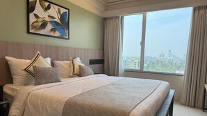 Een hotelkamer met een groot bed, uitzicht op de stad en een schilderij aan de muur.