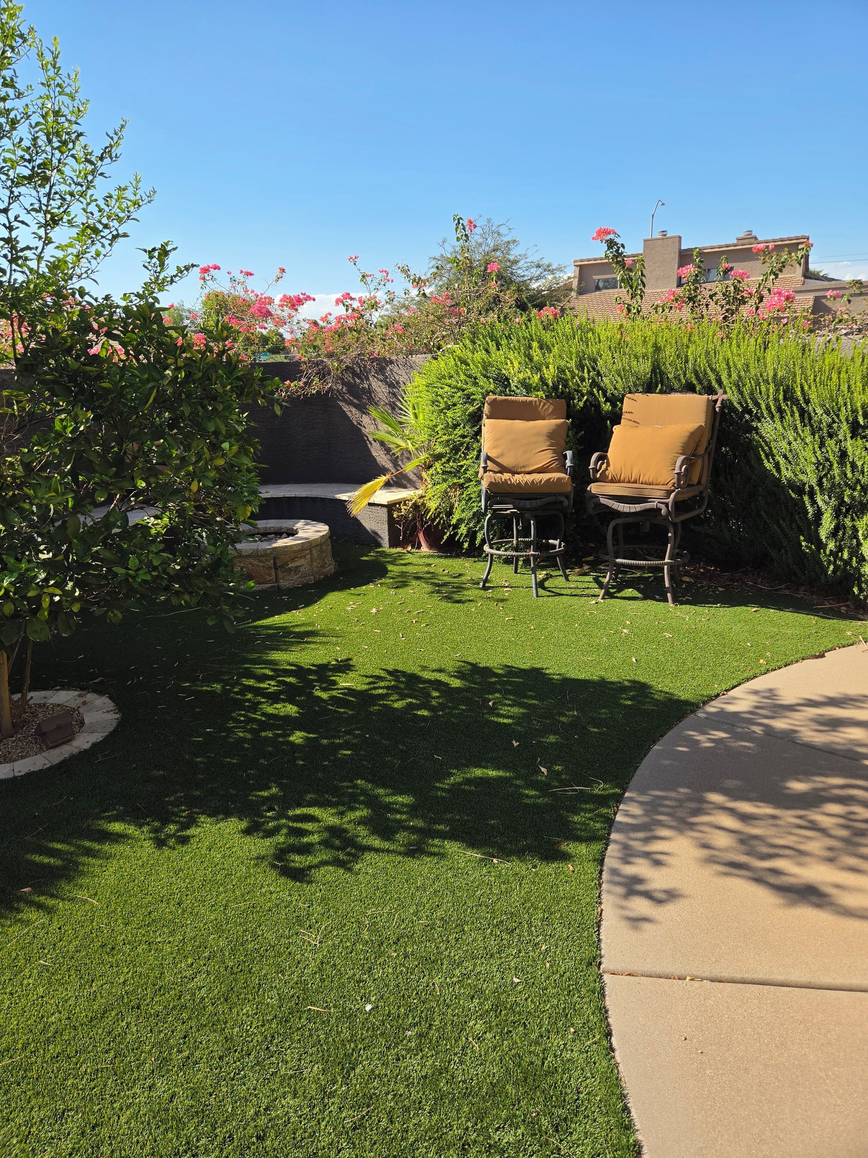 A garden area with a lawn, two chairs, and a stone bench.