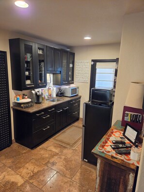 A kitchen with dark cabinets, a microwave, a refrigerator, and a coffee maker.