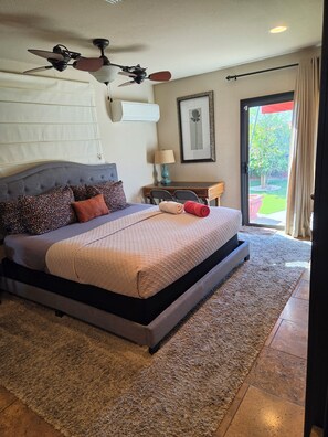 A bedroom with a large bed, a ceiling fan, a window with curtains, and a view of the outdoors. - Cozy Guest Suite with Private Backyard (Mesa)