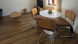 A dining area with a round table, four chairs, a ceiling fan, and a window with curtains. - Historic center apartment  (Narbonne)