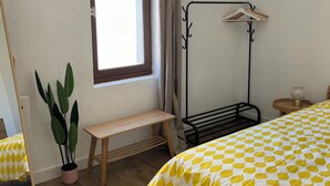 A bedroom with a bed, a window with curtains, a bedside table, a potted plant, and a floor lamp. - Historic center apartment  (Narbonne)