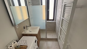 A compact bathroom with a washing machine, a sink, and a mirror. - Historic center apartment  (Narbonne)